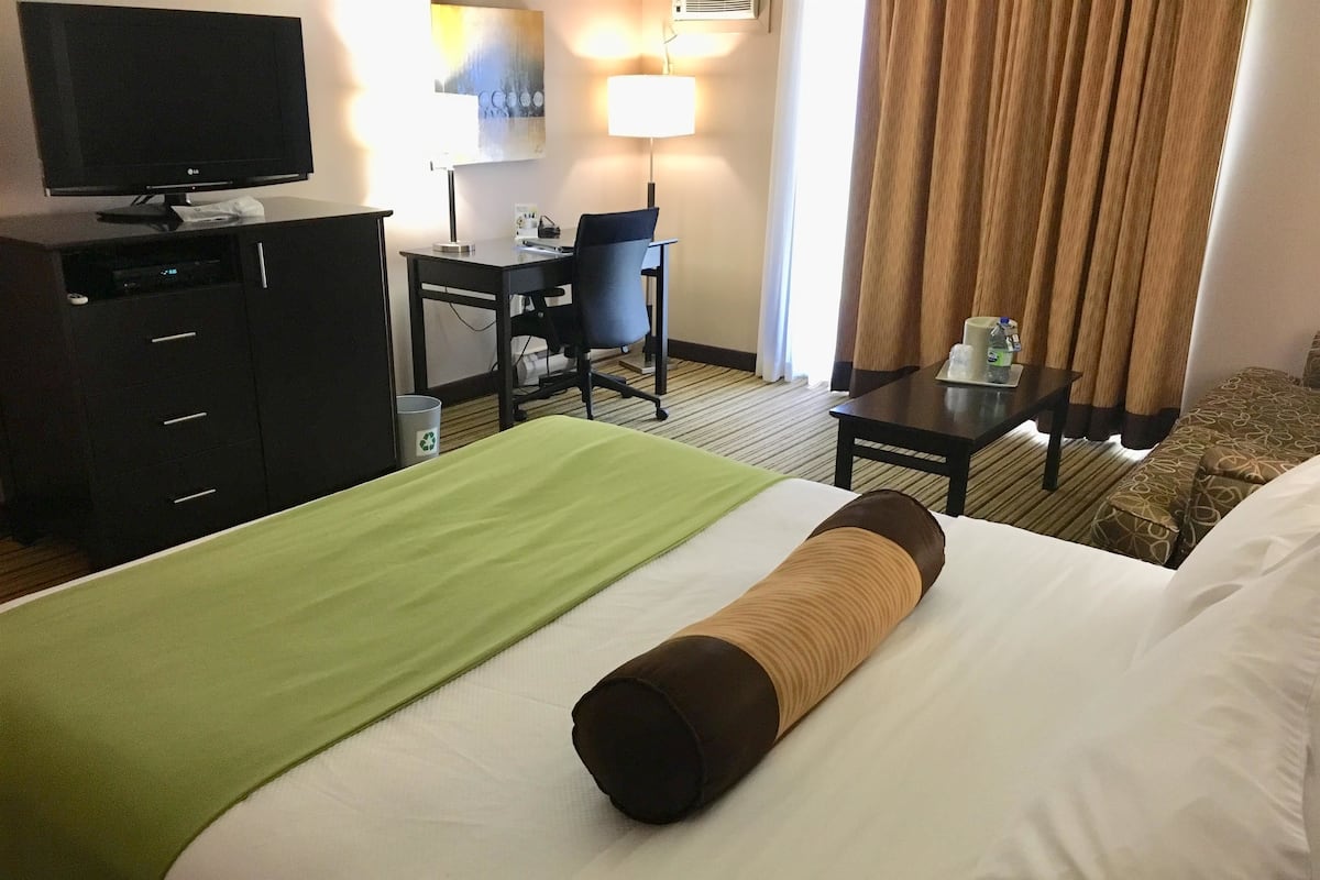 Une chambre d’hôtel avec un lit, un bureau, une télévision et une lampe.