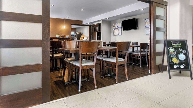 A restaurant with wooden furniture, a menu board, and a television on the wall. - Best Western Plus Mont-Laurier (Mont-Laurier)