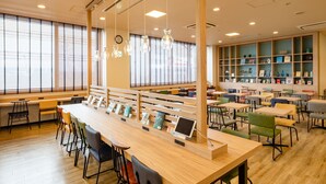 A modern library with wooden tables and chairs, bookshelves, and a large window with blinds. - Comfort Hotel Hamamatsu (Hamamatsu)