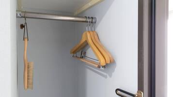 A closet with a hanging rod, a wooden hanger, and a wooden brush.
