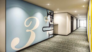 A modern hallway with a large wall mural, carpeted flooring, and recessed lighting. - Comfort Hotel Hamamatsu (Hamamatsu)