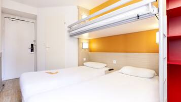 Habitación de hotel con dos camas, una litera, cabecera de madera y una pared de acento roja.