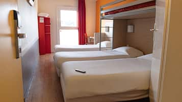 A hotel room with two beds, a red cabinet, a window with curtains, and a bunk bed above.