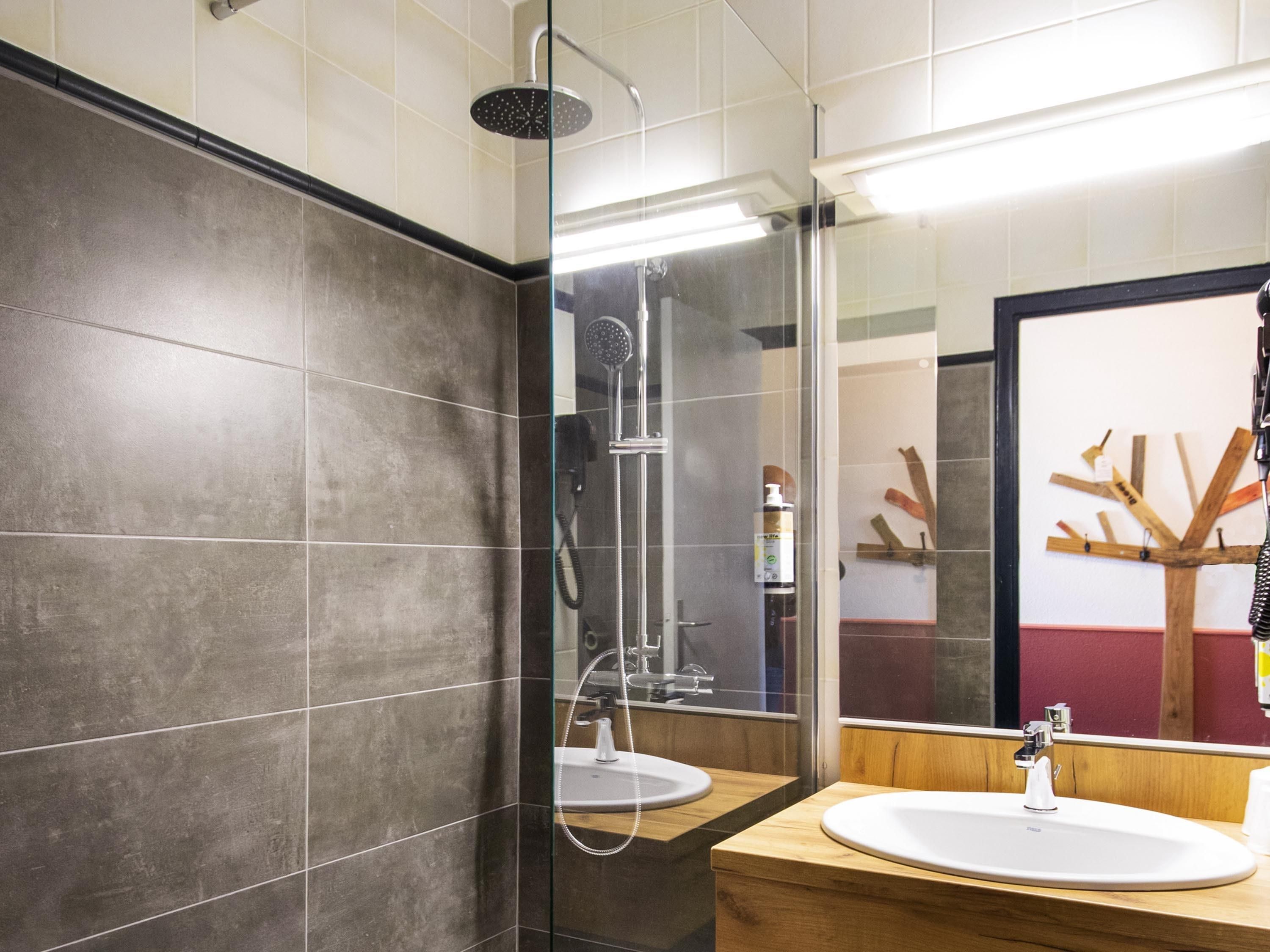 A modern bathroom with a glass shower enclosure, two sinks, and a wooden vanity.