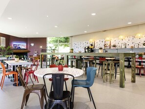 Un comedor moderno con mesas redondas, sillas y una zona de bar.
