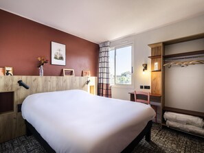 A hotel room with a large bed, a desk, a chair, a wardrobe, and a window with curtains. - Greet Hotel Castres Saïx (Saix)