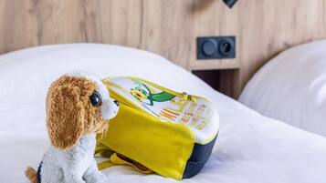 Un jouet en peluche est assis sur un lit, avec un sac à dos jaune à côté.