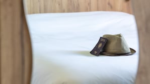 A bed with a hat and passport on it, framed pictures on the wall, and a wooden headboard. - Greet Hotel Castres Saïx (Saix)