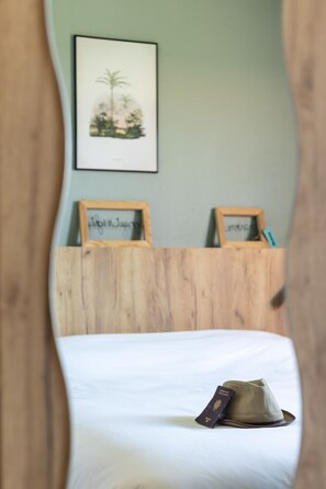 A bed with a hat and passport on it, framed pictures on the wall, and a wooden headboard. - Greet Hotel Castres Saïx (Saix)