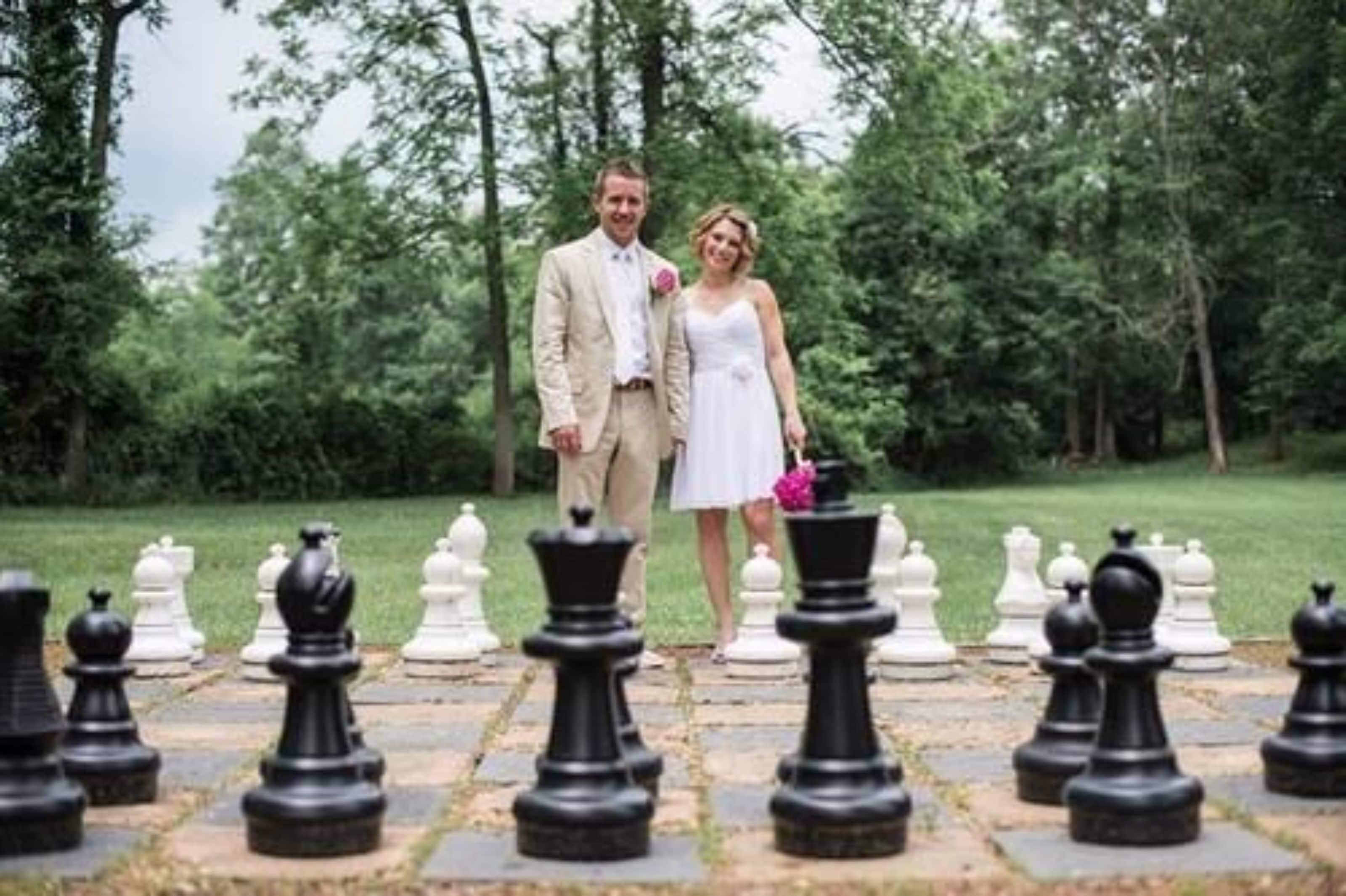 A couple standing on a chessboard with a forest in the background.