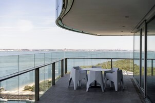 Un balcon moderne avec une balustrade en verre, une table ronde et quatre chaises.