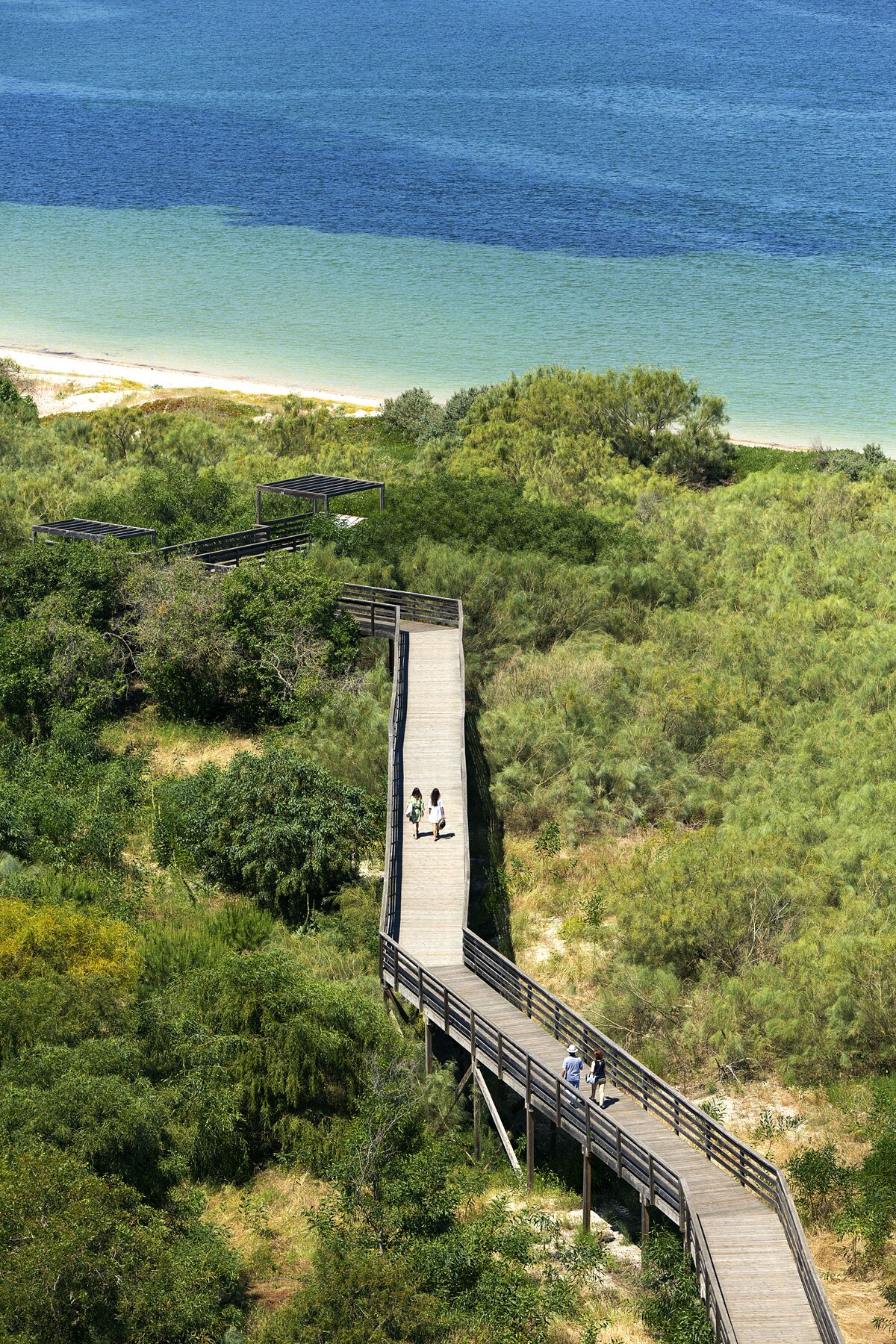 A wooden boardwalk leading to a beach with clear blue water.