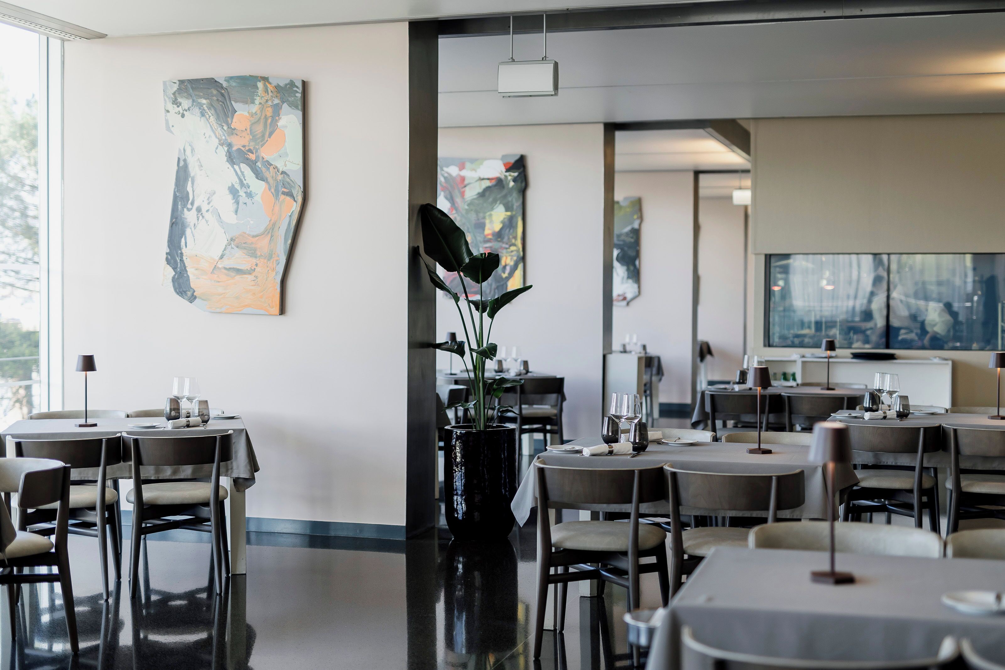Ein modernes Restaurant mit runden Tischen, Stühlen und abstrakter Kunst an den Wänden.