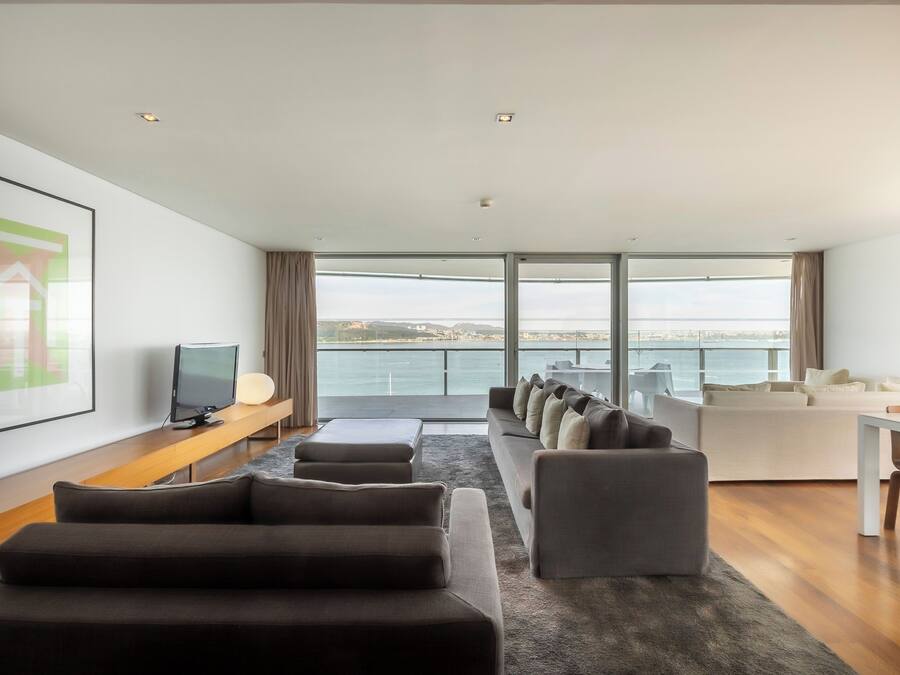 A modern living room with a large window, a flat-screen TV, and a sofa.