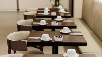 A restaurant with multiple tables, each set with white cups and saucers, and a few with small bowls of food.