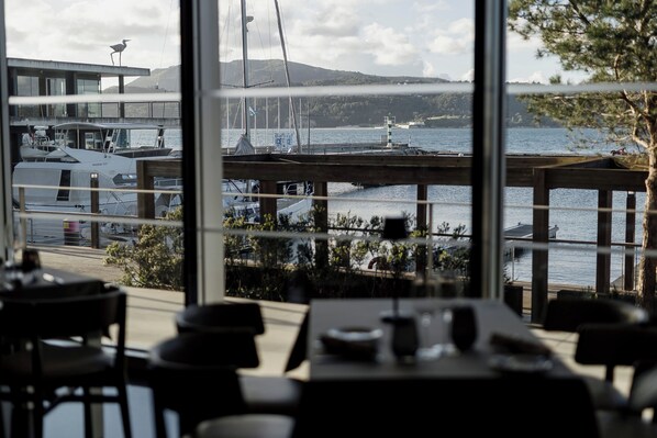 A restaurant with a view of a harbor, including boats and a lighthouse.