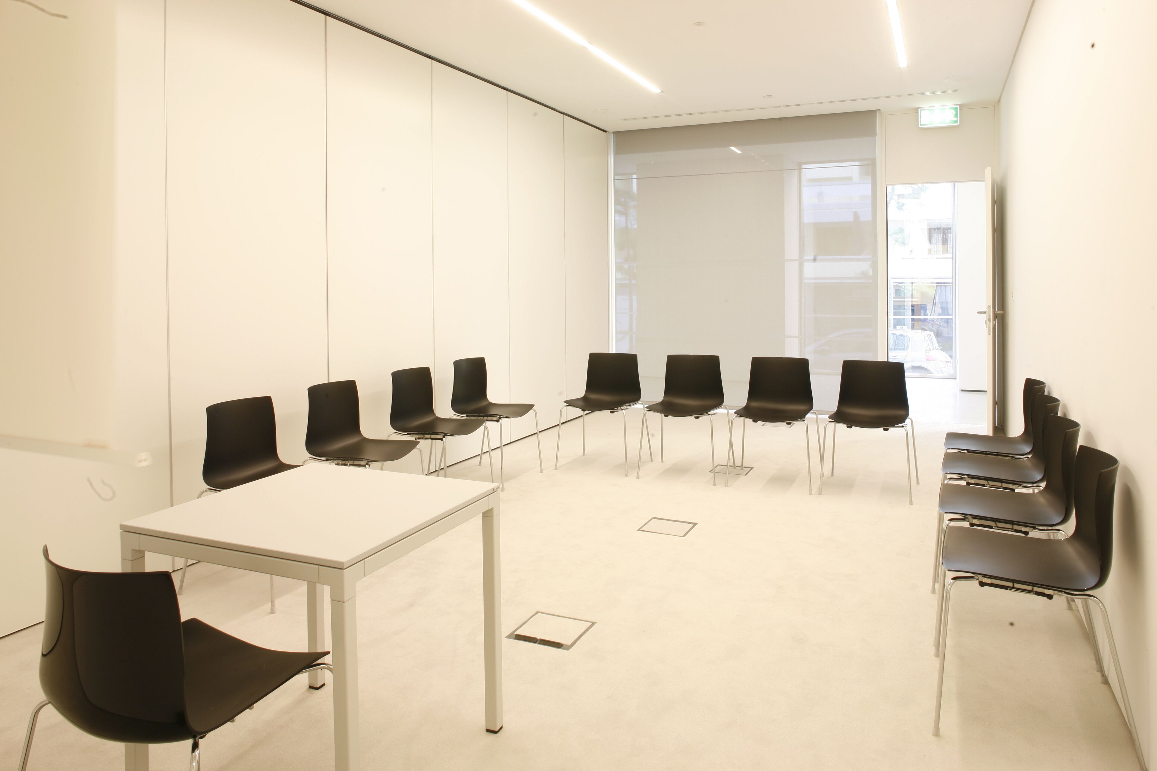 A conference room with a white table and black chairs arranged around it.