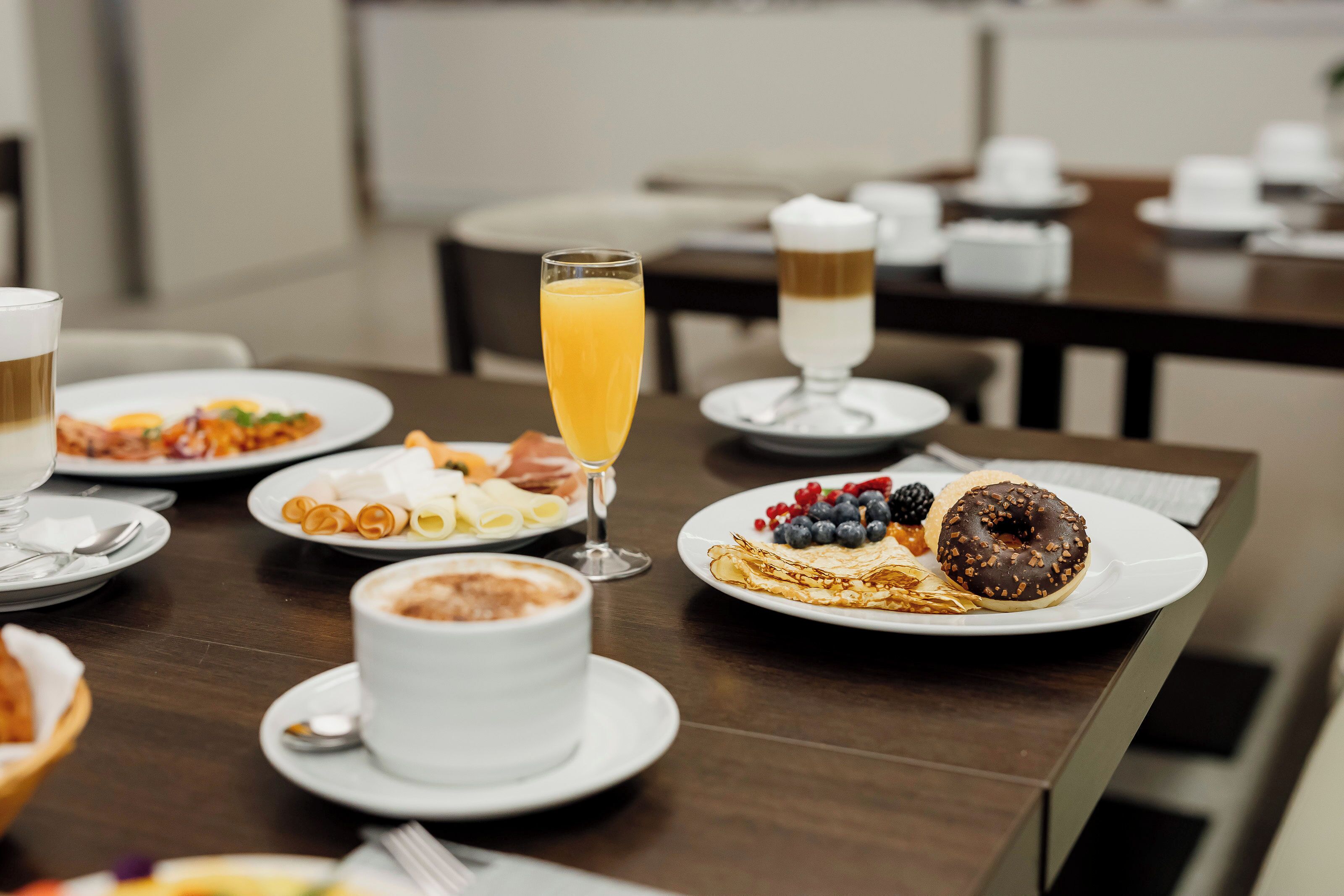 Desayuno con platos de comida, un vaso de jugo de naranja y una taza de café.
