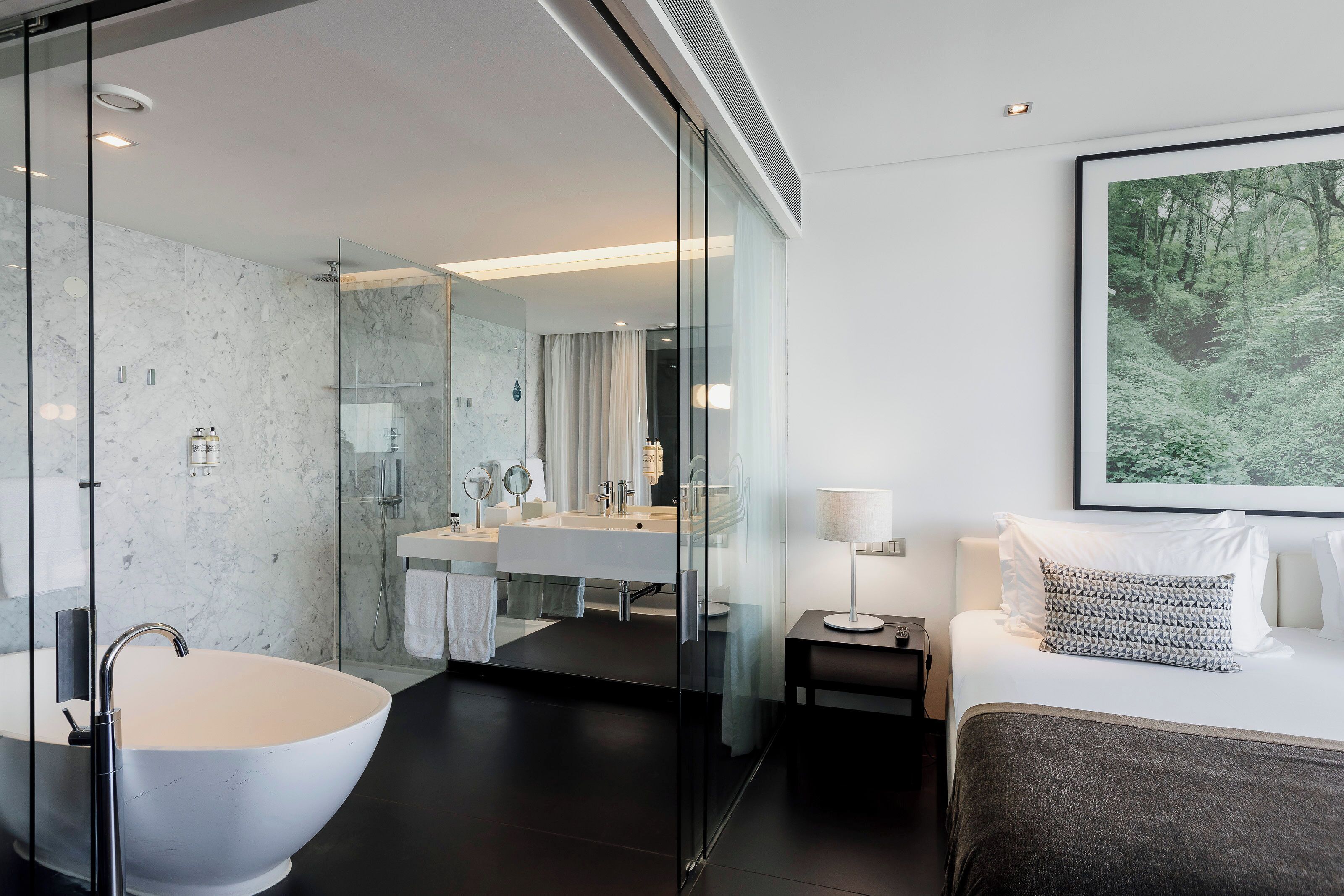 Un bagno moderno con una vasca da bagno freestanding, una cabina doccia con pareti in vetro e un grande specchio.