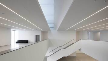 A modern interior with a staircase, white walls, and a seating area.