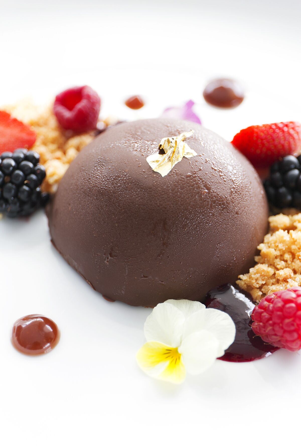 A dessert with chocolate mousse, garnished with berries and flowers.