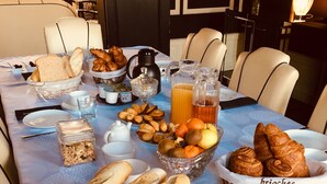 A breakfast table with bread, pastries, fruits, and beverages. - Maison de Plumes (Heuchin)