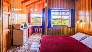 A wooden cabin with a bed, a small kitchenette, and a view of the outdoors. - Hotel Mango Valley (San Roque)