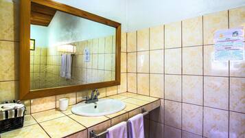 A bathroom with a sink, mirror, and tiled walls.