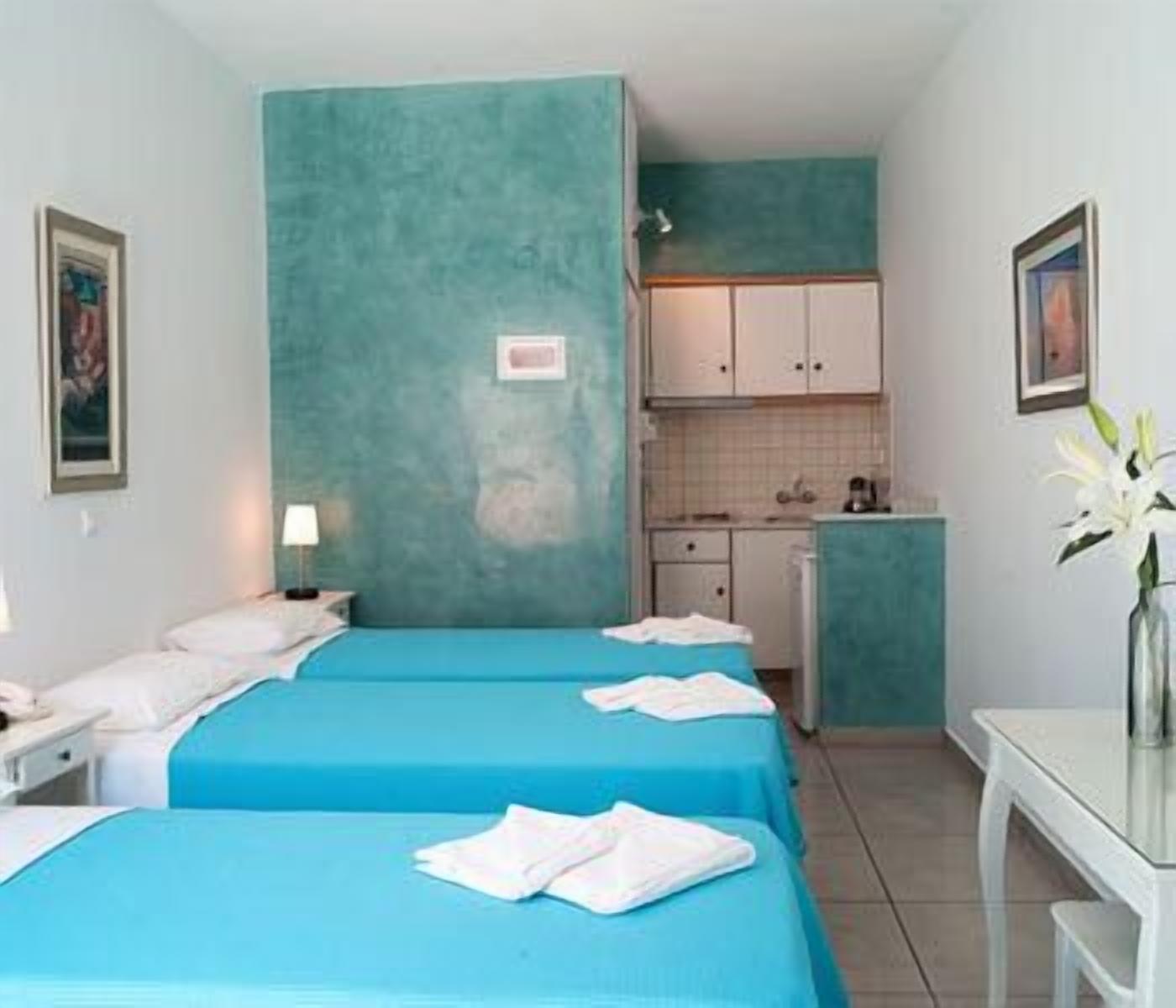 Een kamer met twee bedden, een klein keukenhoekje en een badkamer.