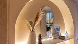 A modern interior with a white vase and pampas grass on a shelf, a framed picture, and a small vase.