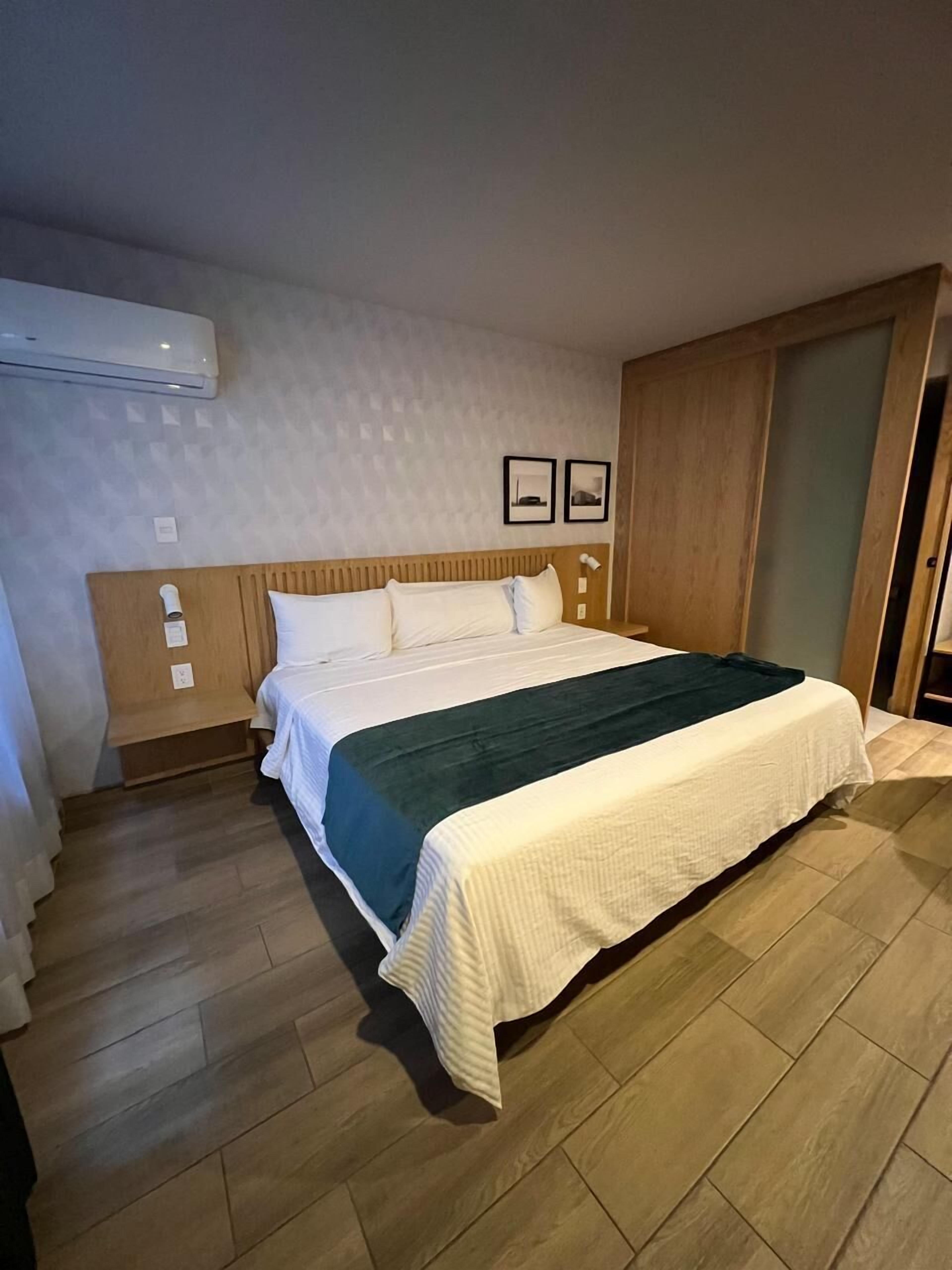 A bedroom with a bed, wooden headboard, and a wooden wardrobe.