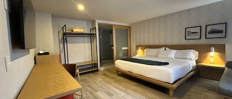 Una habitación de hotel con cama, escritorio, silla, televisor y armario.