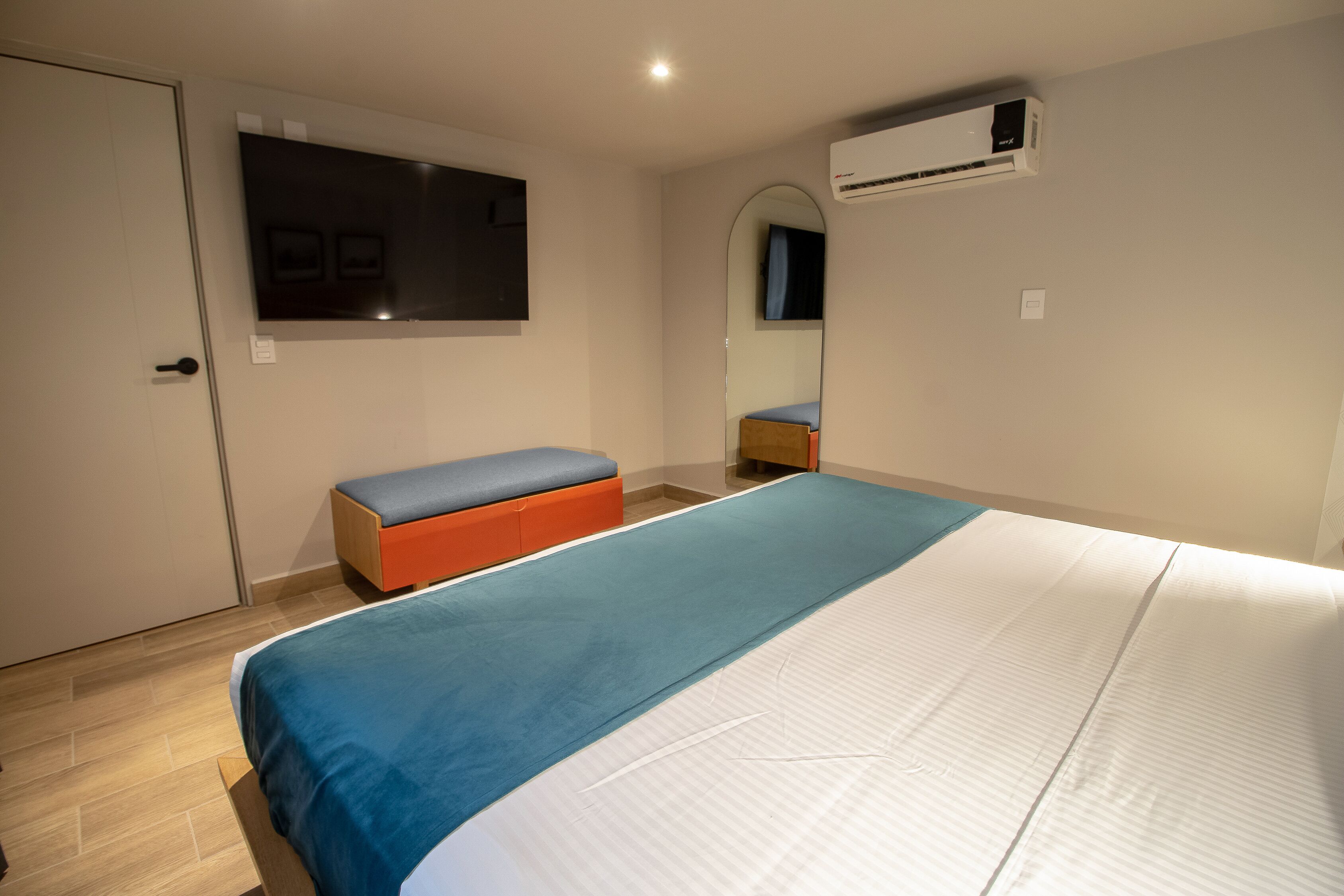 Una camera da letto con un letto, una panca, una TV e un condizionatore d'aria.