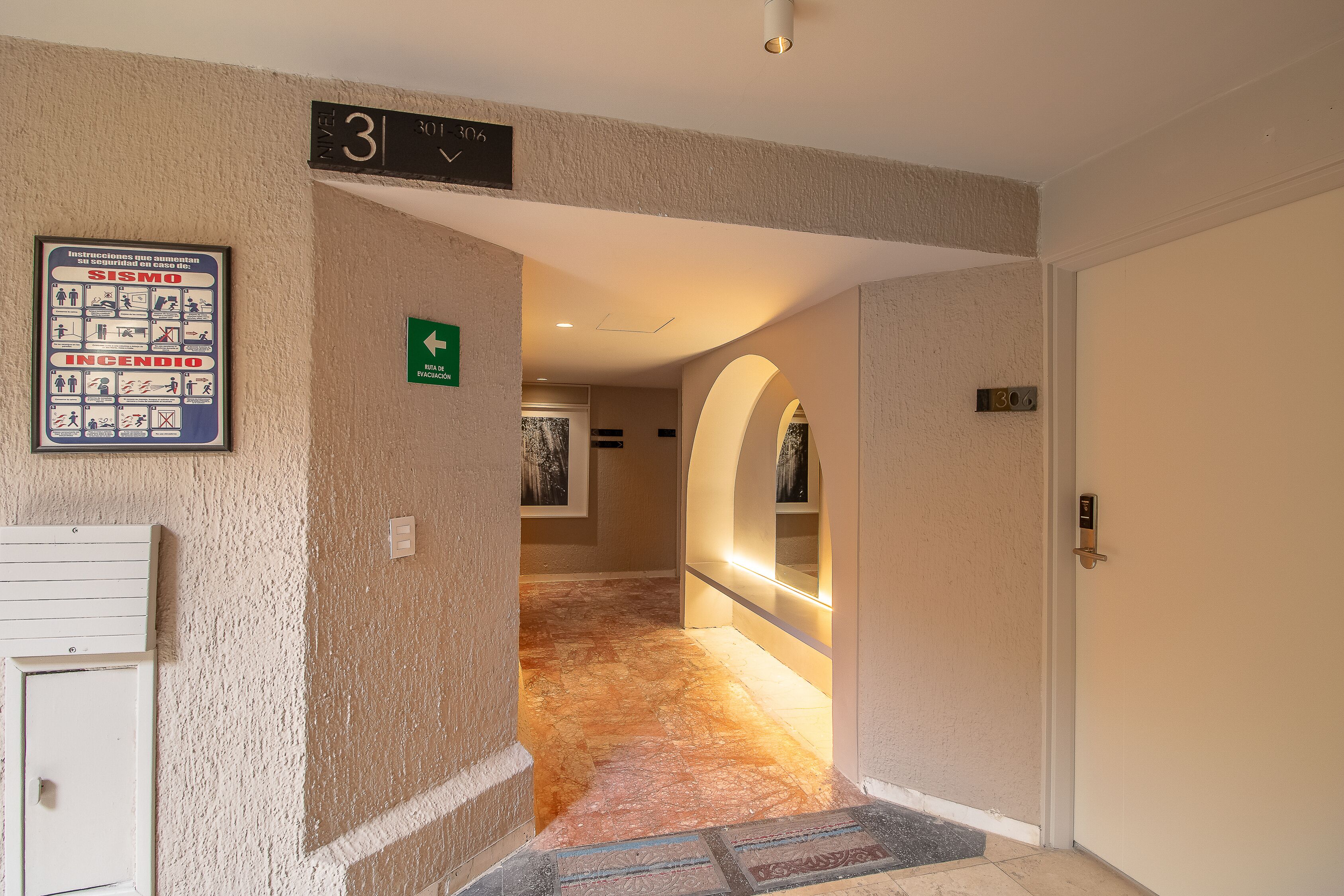 A hallway with a sign indicating room number 3, a fire safety poster, and a door with a number plate.