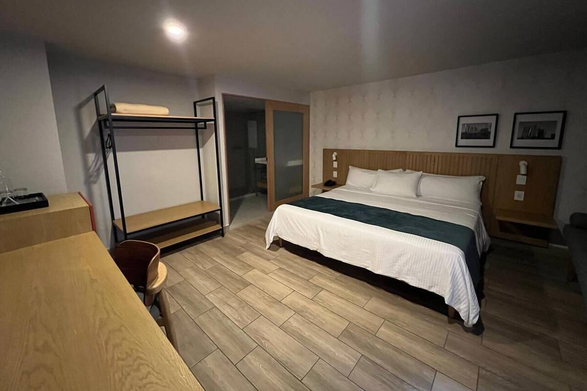 Una habitación de hotel con cama, escritorio, silla y armario.