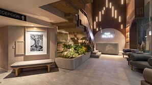 A modern reception area with a reception desk, a bench, a staircase, and a seating area with sofas.