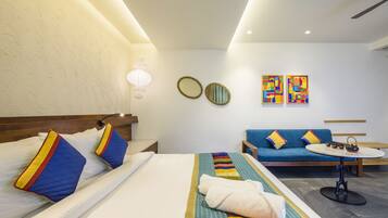 Una habitación de hotel con una cama, un sofá, una mesita y obras de arte en la pared.