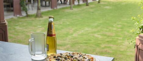 Pizza sobre una tabla de madera en una mesa, junto a una botella de vino y un vaso de agua.
