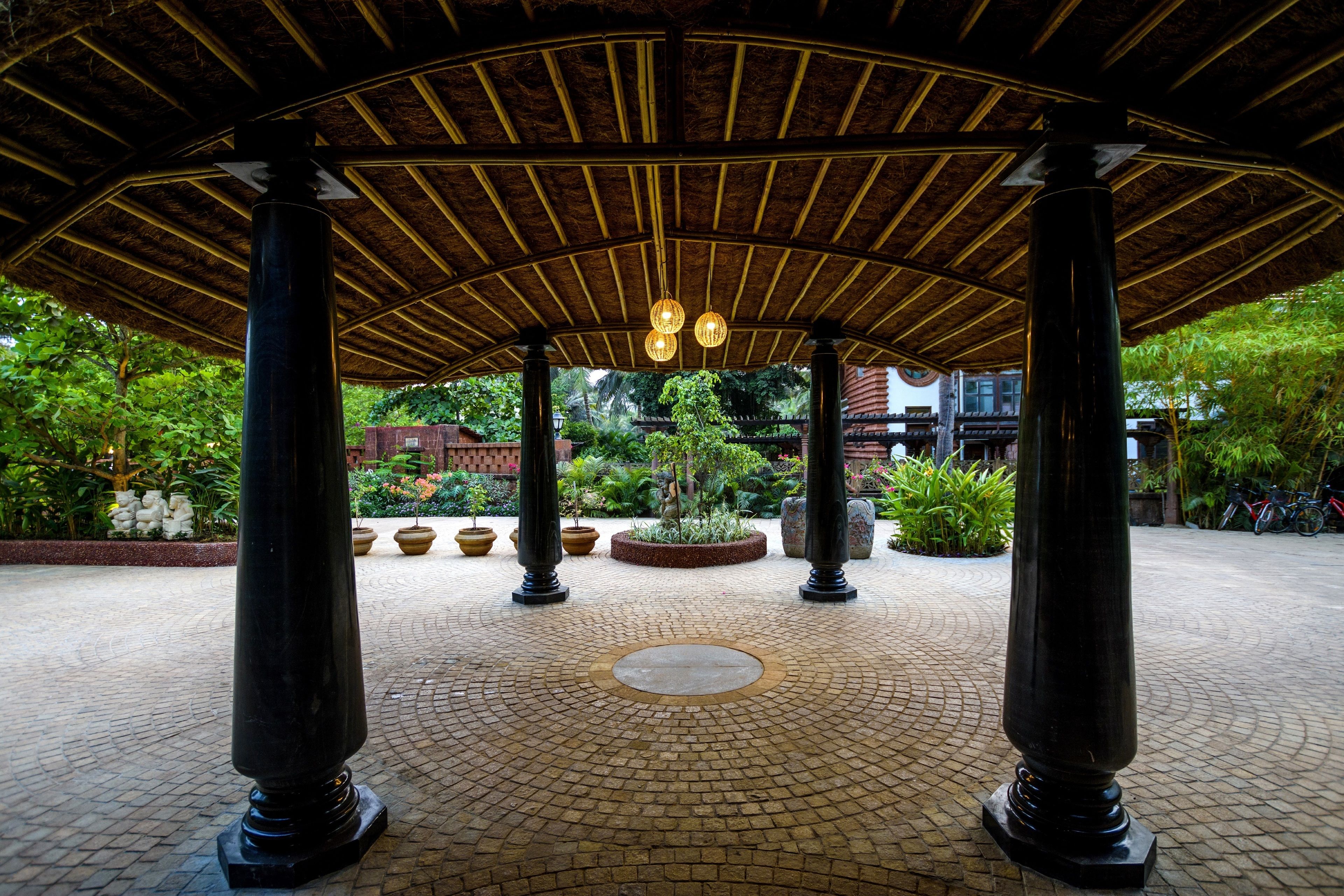 Un espacio al aire libre techado con suelo de baldosas, columnas e iluminación colgante.