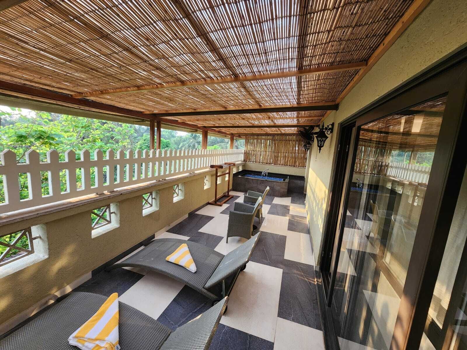 A covered outdoor seating area with checkered flooring, lounge chairs, and a pool.