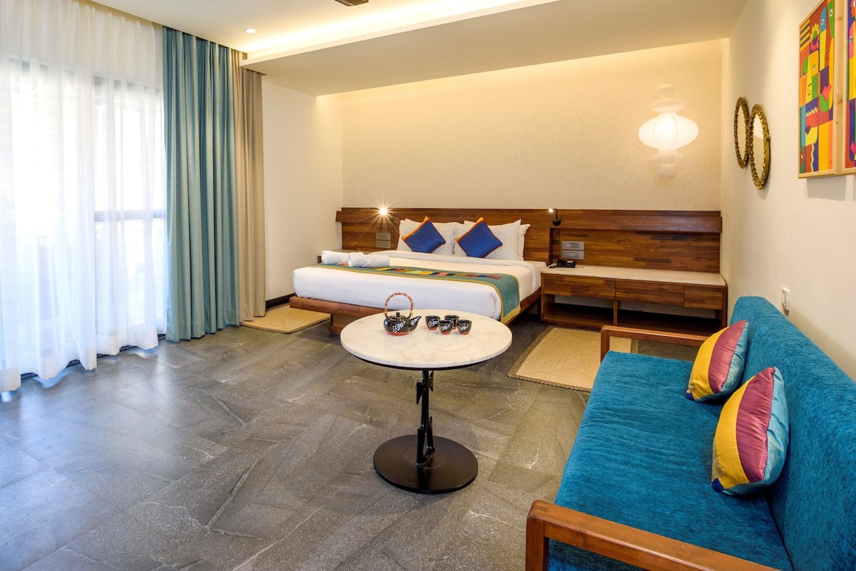 A hotel room with a bed, a blue sofa, a small round table, and a cabinet.