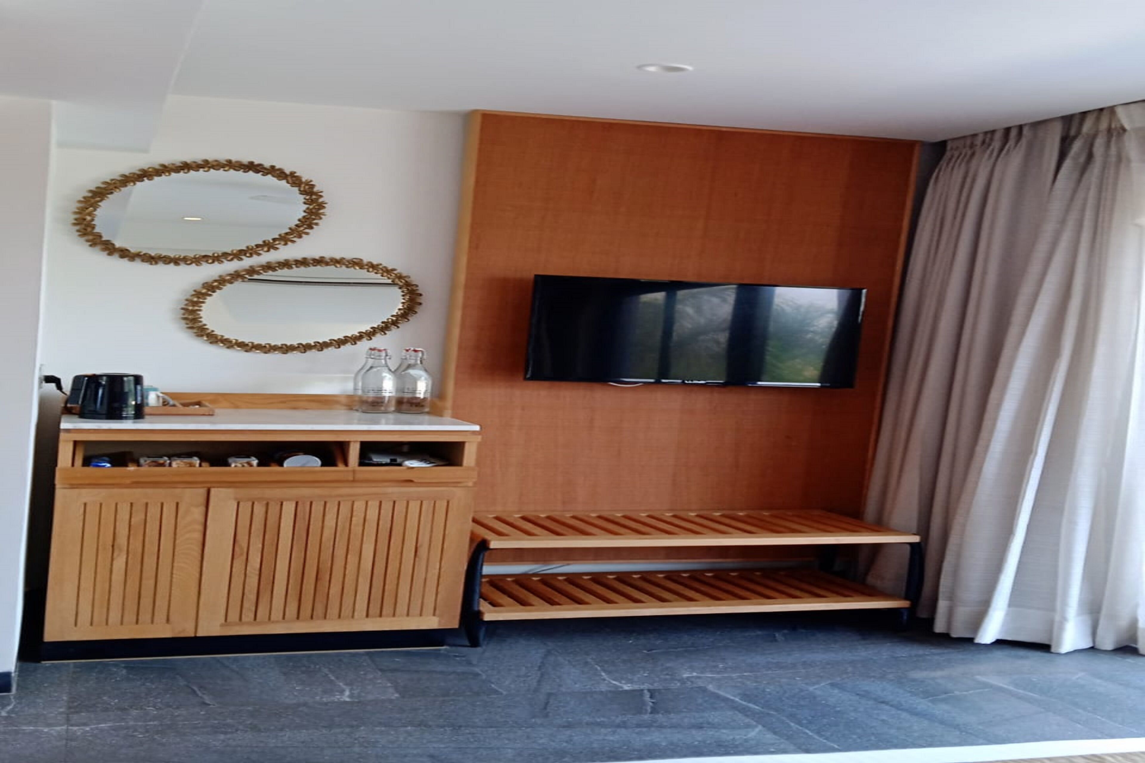 Ein modernes Zimmer mit einem Holzkabinett, einem flachbildfernseher an der Wand und einem Fenster mit Vorhängen.