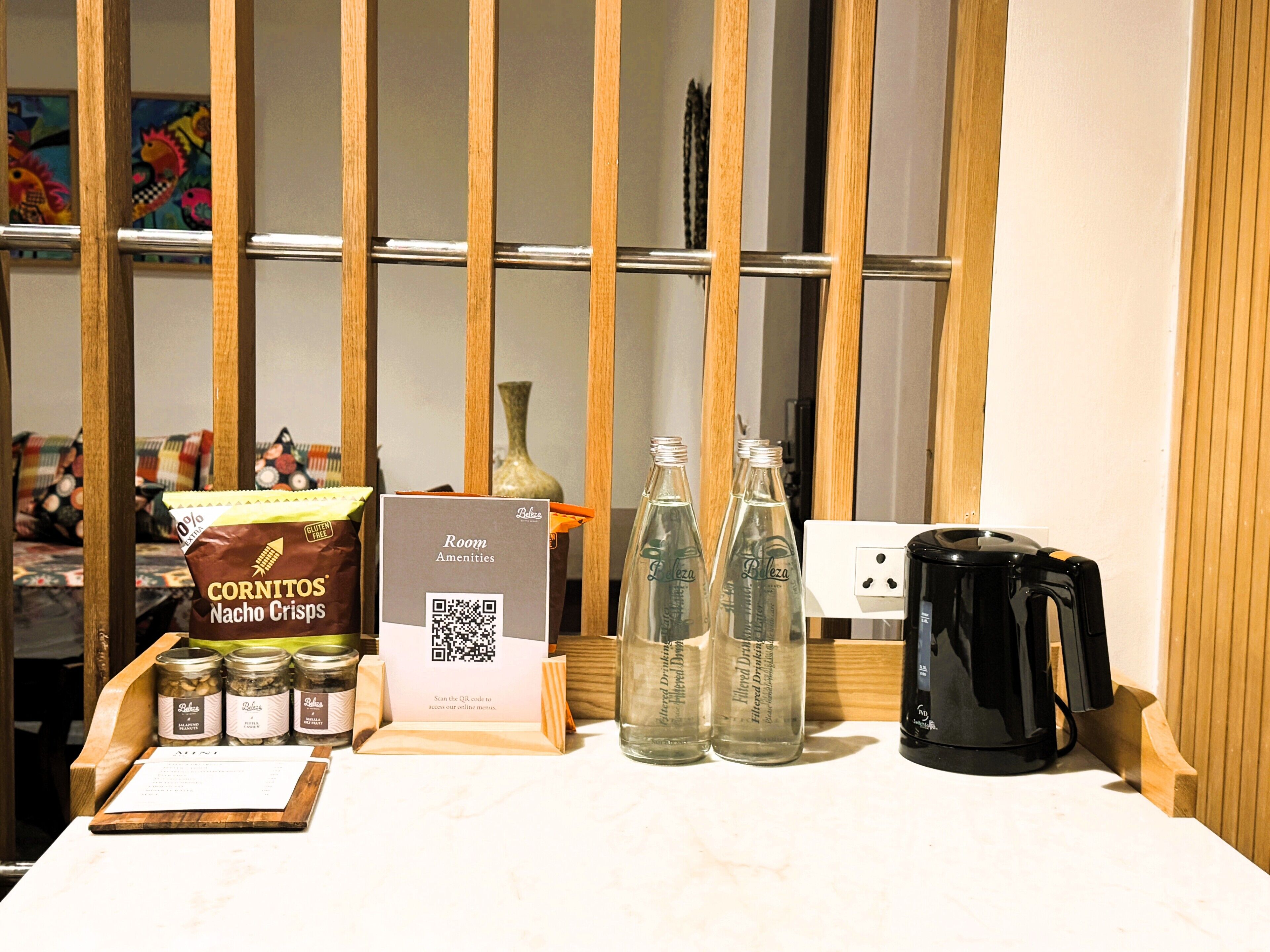 A table with snacks, a QR code for amenities, and a coffee maker.
