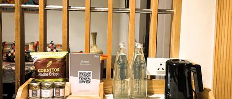 A table with snacks, a QR code for amenities, and a coffee maker.