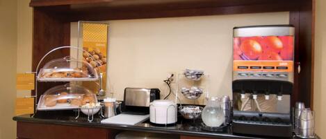 A breakfast bar with a coffee machine, toaster, and various food items.