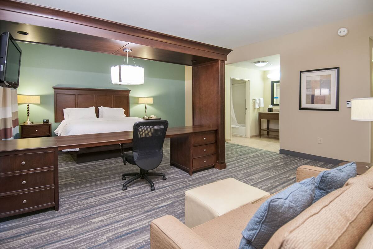 A hotel room with a bed, desk, office chair, and a sofa.