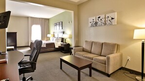 A hotel room with a bed, a sofa, a desk with a chair, a TV, and artwork on the wall. - Sleep Inn & Suites Abilene Near University (Abilene)