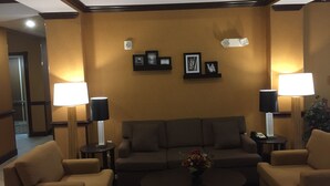 A hotel lobby with a brown sofa set, two side tables with lamps, framed pictures on the wall, and a small table with a vase of flowers. - Sleep Inn & Suites Abilene Near University (Abilene)