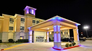 A hotel entrance with a covered waiting area, a prominent sign, and a well-lit facade. - Sleep Inn & Suites Abilene Near University (Abilene)