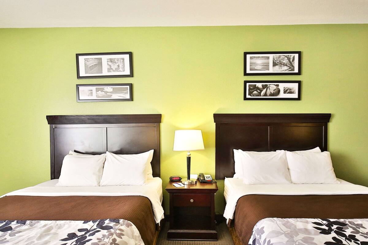 Une chambre d’hôtel avec deux lits, une table de chevet avec une lampe et des tableaux encadrés au mur.